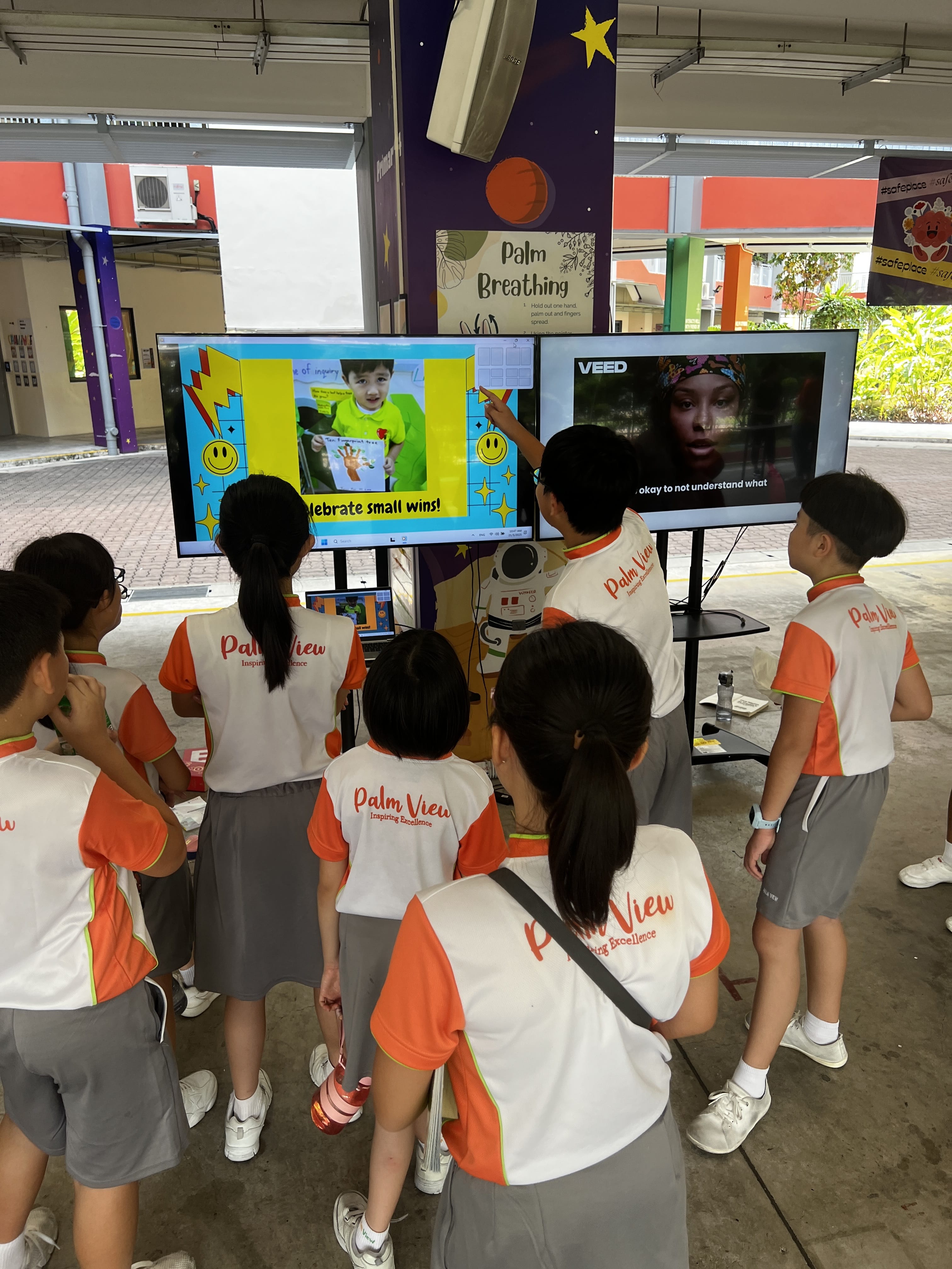 A group of students looking at the a TV screen of photos of their peers feeling happy